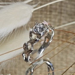 Bague aux formes entrelacées avec une pierre centrale diamant, présentée sur un miroir